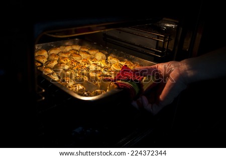 Woman hand taking out hot cakes from oven