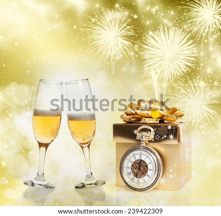 Golden gift box, champagne glasses and clock close to midnight on sparkling holiday background