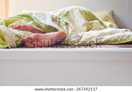 Close up of two feet in a bed - relaxing sleep