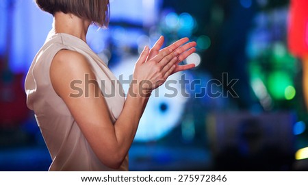 Woman clapping - stage in the background