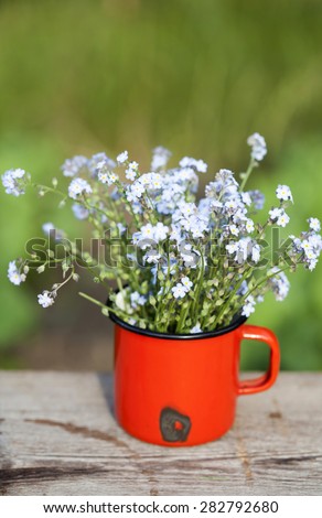 Summer background with forget me not flowers in a jar on wooden background
