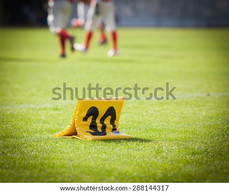 american football game yard markers with out of focus players in the background