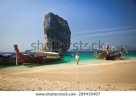 Woman walking on Tropical beach, longtail boats, Andaman Sea, Thailand