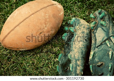 close up of an american football and sports shoes covered with mud