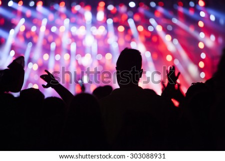 Crowd at concert - Cheering crowd in front of bright colorful stage lights