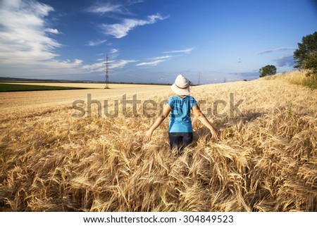 Young woman enjoying nature and sunlight in wheat field at sunset