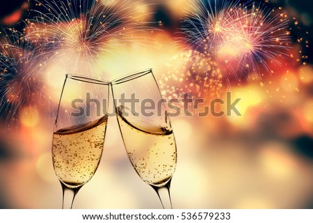 toasting with champagne glasses against holiday lights and new year fireworks