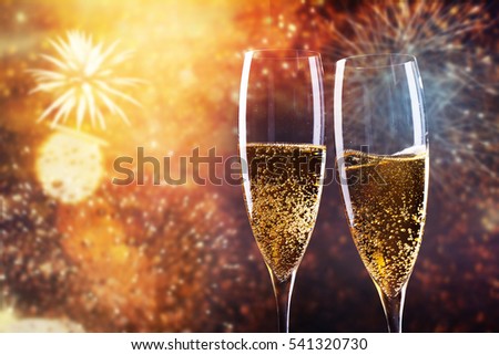 toasting with champagne glasses against holiday lights and new year fireworks