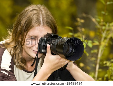 Young female photographer in autumn forest
