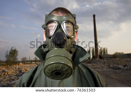 Bizarre portrait of man in gas mask on smoky industrial background with pipes after nuclear disaster
