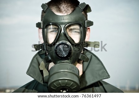 Bizarre portrait of man in gas mask on smoky industrial background with pipes after nuclear disaster