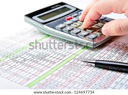 Close-Up Of A Spreadsheet With Pen And Calculator.