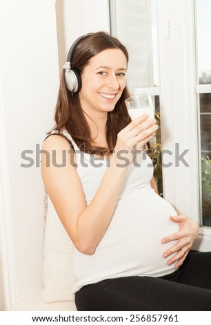 pregnant women drink a glass of milk and listening to music