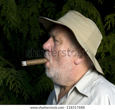 Bearded cigar smoker with the hut and black background