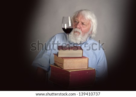 Old man with books and a glass of red wine