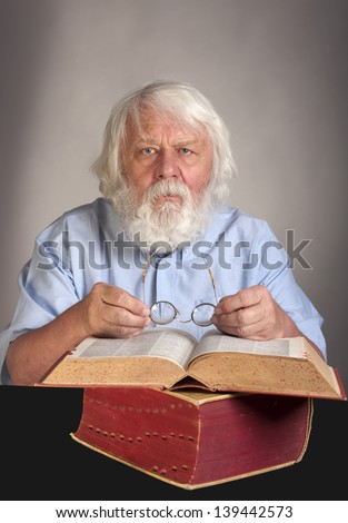 Old man reading a book, scientist and teacher with beard and glasses