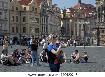 PRAGUE - JULY 1: Group of unidentified tourists, resting on the historic Old Town Square with a young lady, taking a picture in hot summer day in front of Old City Hall. Czech Republic, July 1, 2009