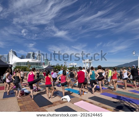 VANCOUVER - JULY 1, 2014: Celebration of the CANADA DAY is provided in cities and towns across Canada. Sport activity of Canadians is demonstrating by yoga excercising by Canada Place in Vancouver.