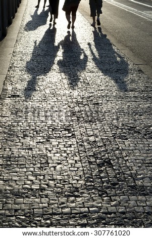 Walkers and shadows on the sidewalk, Cobblestones on the pavement