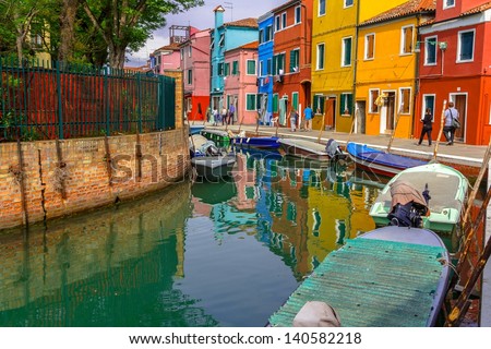 Typical Burano street with colorful houses and people walking around.