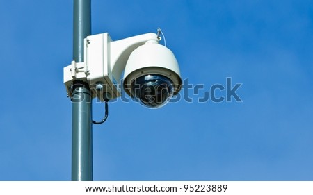 360 degrees surveillance camera on a pole, blue sky.
