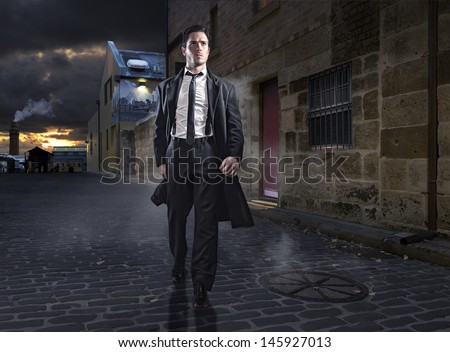 Old style man in factory area wearing a black suit and coat
