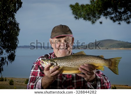 Elderly fisherman proudly shows off his brown trout
