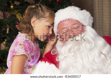 Little girl whispers her Christmas list to Santa