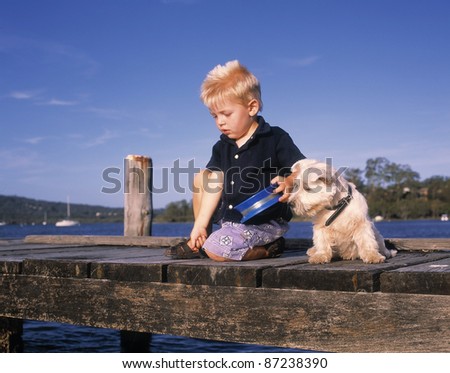Young boy and his dog fishing of a wharf