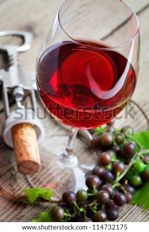 Glass of red wine with grapes on table