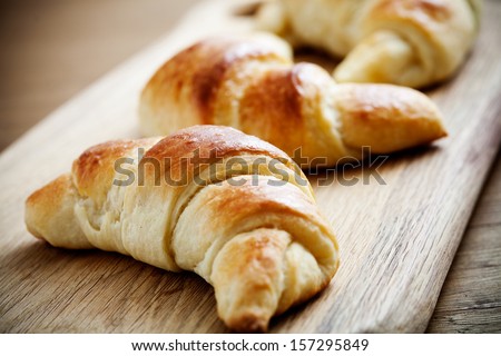 Fresh homemade croissants on wooden table, selective focus