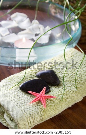 Bowl of water with candle and rose petals, spa treatment for relaxation
