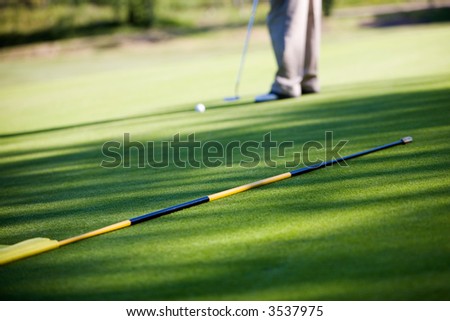 Close-up of man putting golf ball in to hole