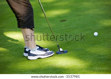 Close-up of junior golfer putting golf ball in to hole