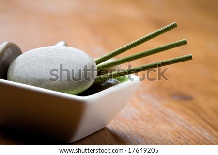 Green incense sticks and massage stones on bowl