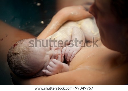 Newborn baby on his mothers arms right after delivery