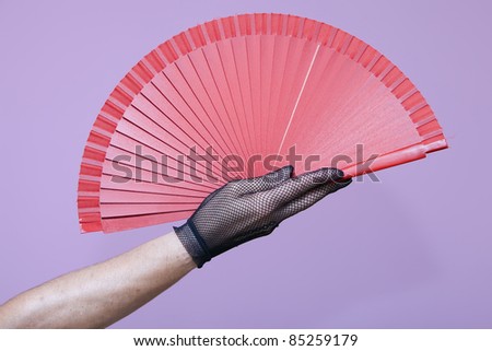 with a gloved hand holding an open fan