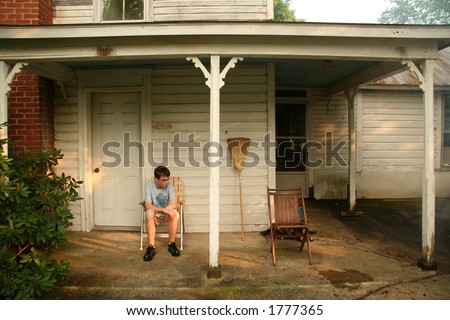 Boy sitting on porch looking down.