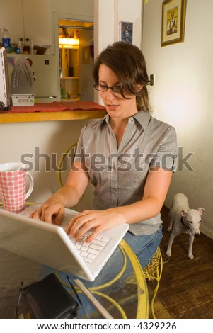 Woman using laptop computer at home with pet dog