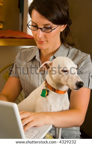 Woman using laptop computer with pet dog in lap.