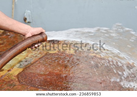 Arm of person cleaning of a  boat   with water rubber tube