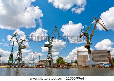 three old cranes standing by the water in old shipyard in Gdansk, Poland