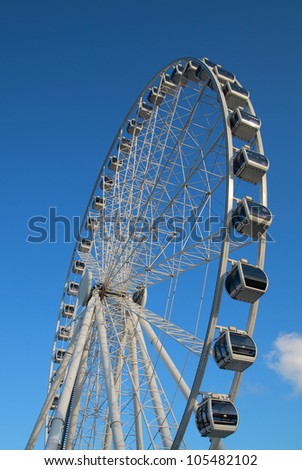 Ferris wheel brightly lit with the sun against blue sky