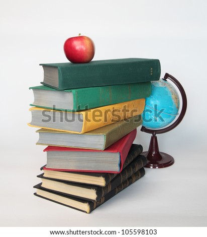Pile of old books with apple on top and globe on white as a symbol of study and knowledge.