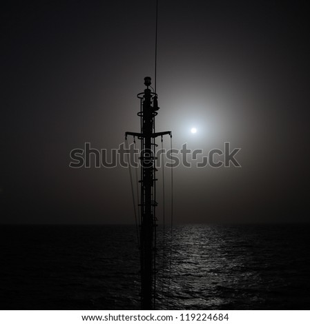 Outlines of ship mast against setting sun. Nautical background. Shot with ND filter.