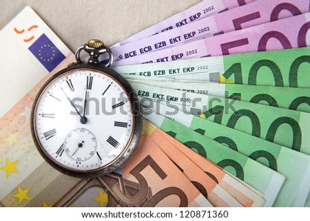 Time and Money concept image. Euro banknotes with vintage watch.