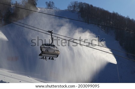 Ski lift gondola against automized artificial snow