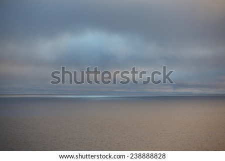 Picturesque northern seascape with blue rays of arctic sun seeping through the clouds