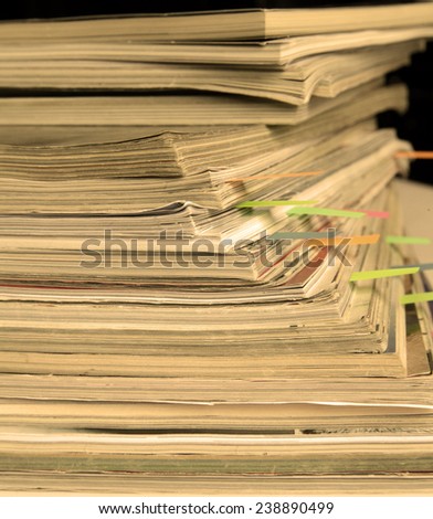 Dingy sepia-style photo of pile of old magazines with bookmarks