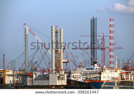 Industrial background: shipyard offshore installations construction site with cranes and steel structures  against blue sky.